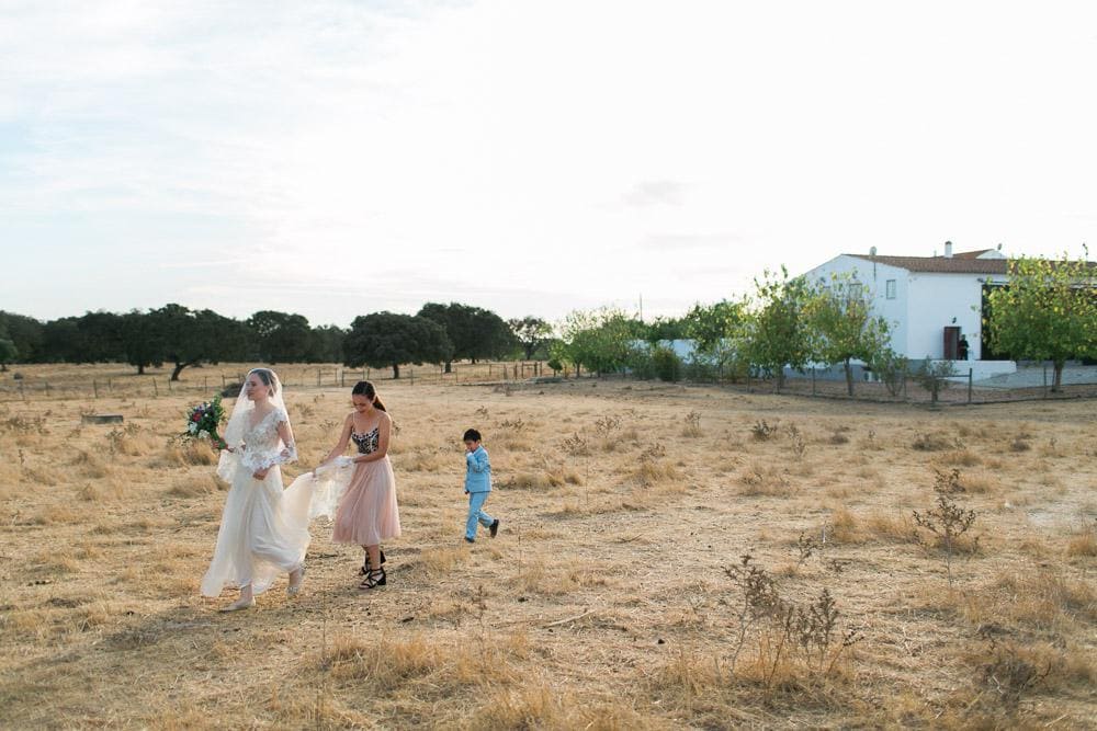 bride walking by the field to the tree ceremony Rustic boho wedding at countryside Alentejo Herdade dos Alfanges #rusticwedding #countryside #portugalvenue jesuscaballero.com