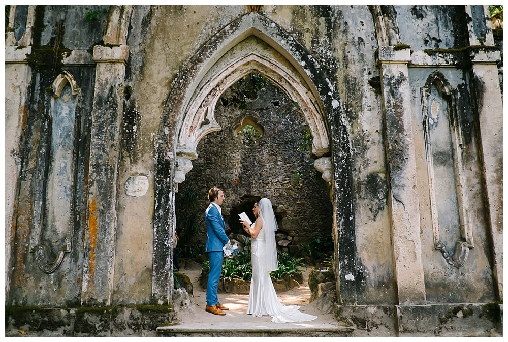 couple reading vows in the middle of the door of at the chapel ruins in monserrate palace at sintra park