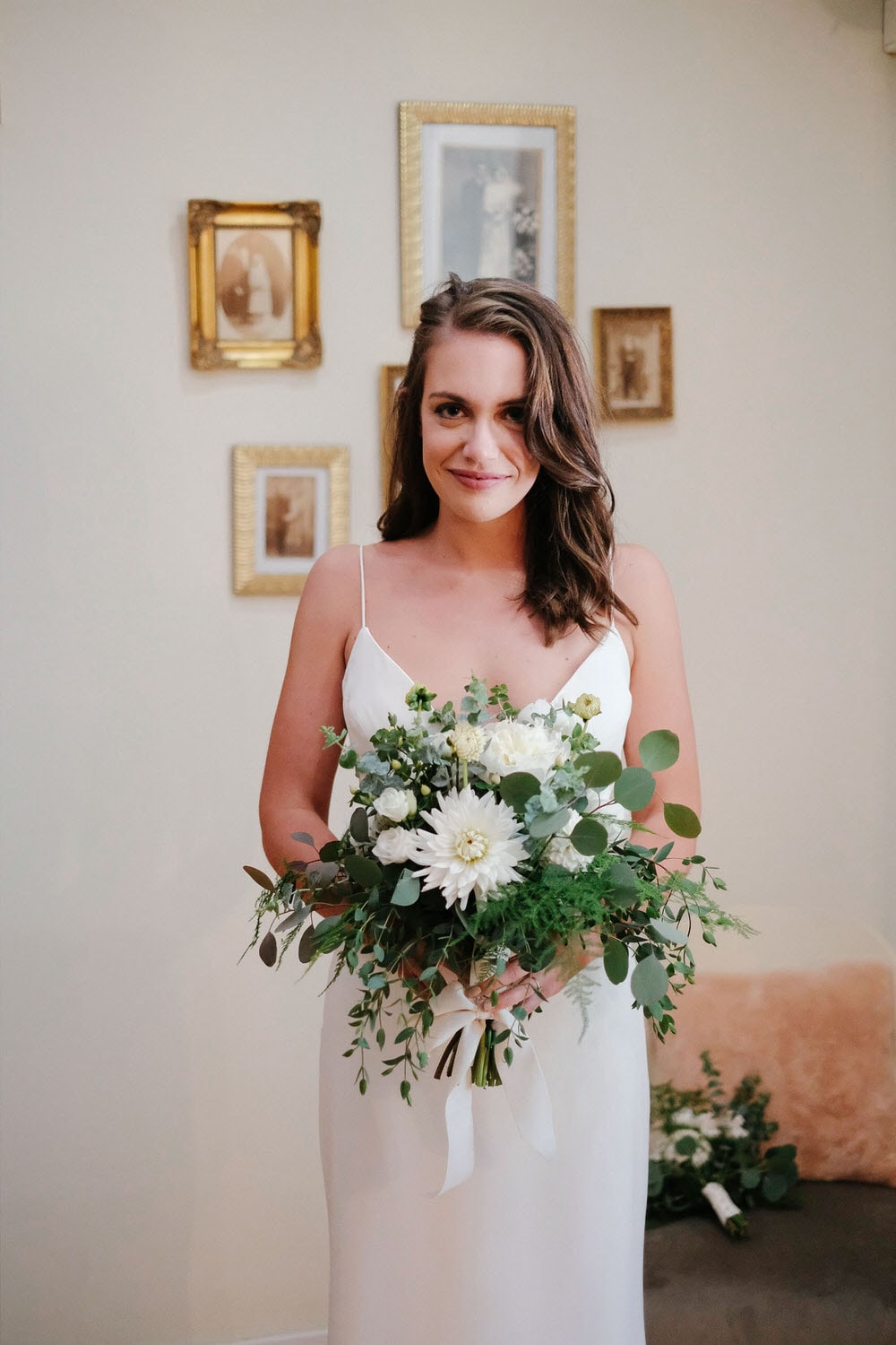 Bride looking straight ahead with a bouquet of white flowers and green leaves
