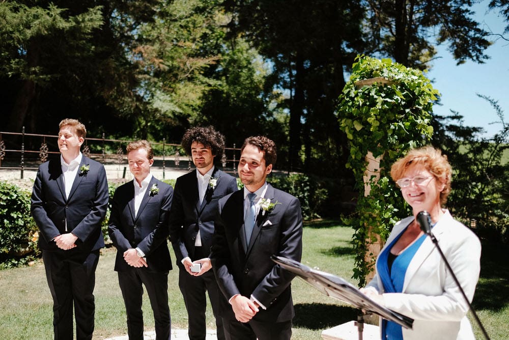 The groom and bestman and groomsmen, smiling and confident, waiting for the bride's arrival at the altar
