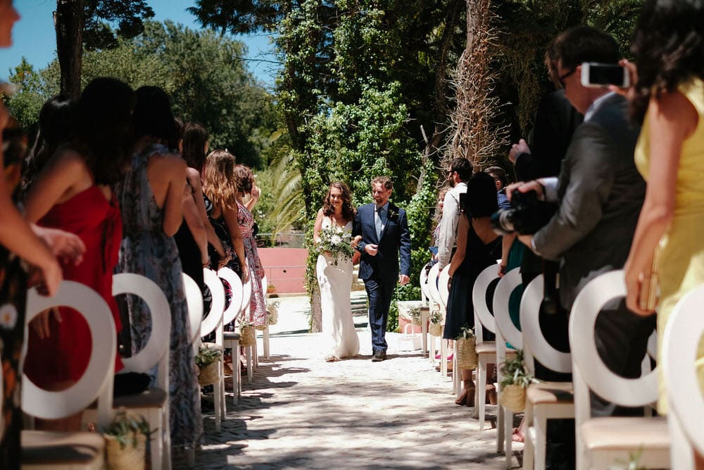 The bride and her father walk towards the altar, as all the guests enjoy watching them walk towards the altar