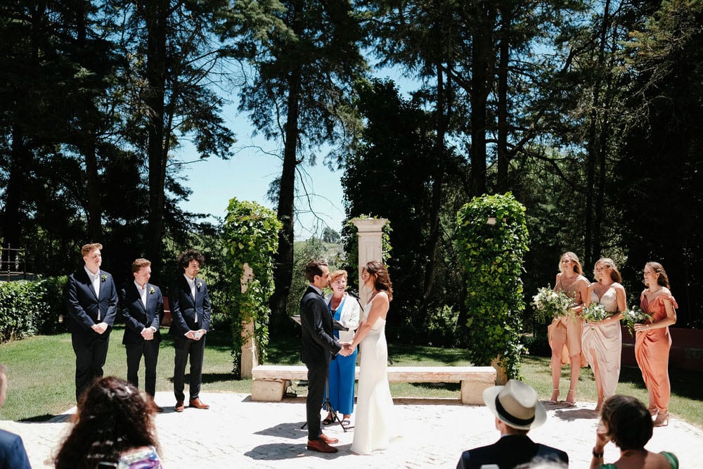 Quinta da Bichinha rustic destination wedding . The wedding party stands in formation around the couple, with a typical American wedding scene to one side, girls on one side and boys on the other, with the celebrant in the middle with the couple