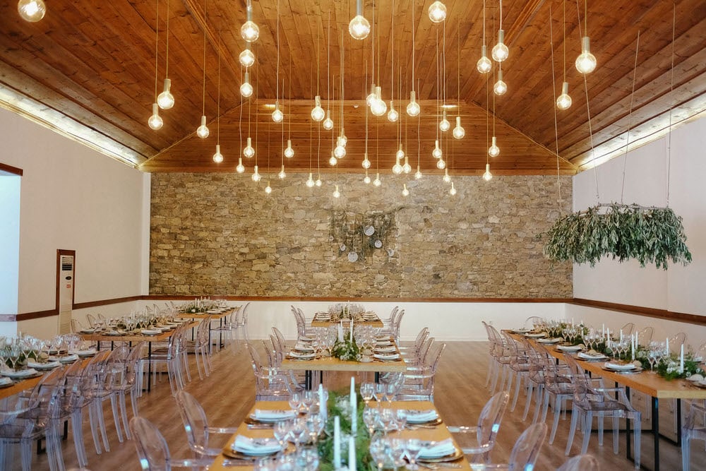 Quinta da Bichinha rustic destination wedding . The wedding hall, with tables set up symmetrically and a vertical garden hanging over the tables in warm tones with the green of the plants at quinta da bichinha