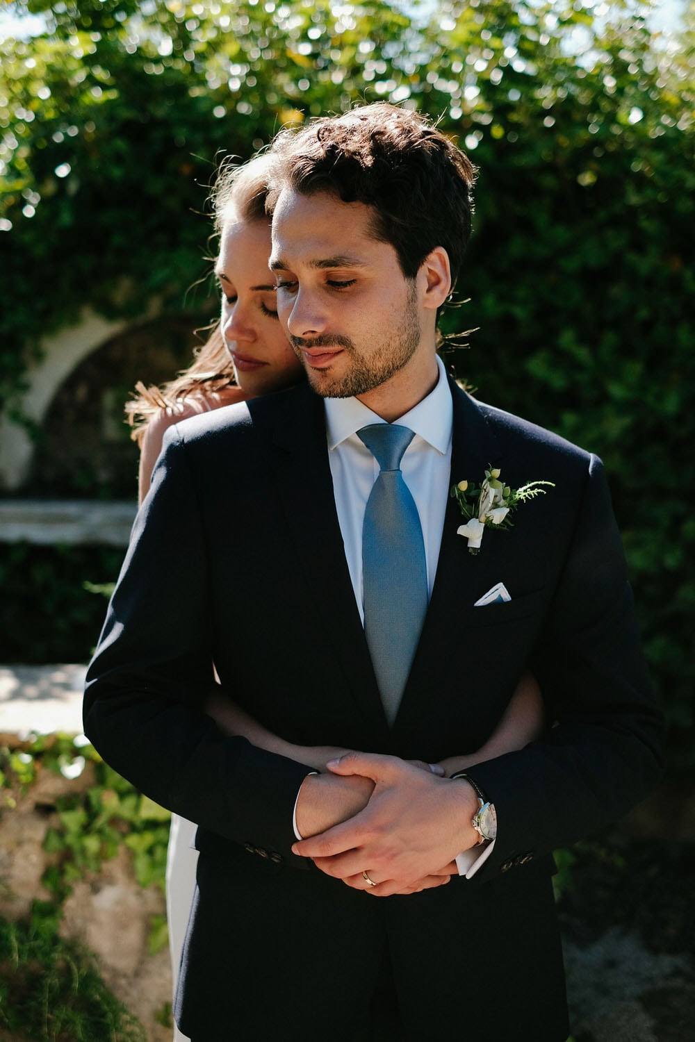 he bride leans on the groom's shoulder from behind, surrounded by the forest vegetation and ancient ruins of the quinta da bichinha