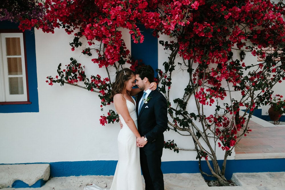 The bride and groom gaze at each other in front of a beautiful bougainvillea at Quinta da Bichinha with a typical Portuguese facade