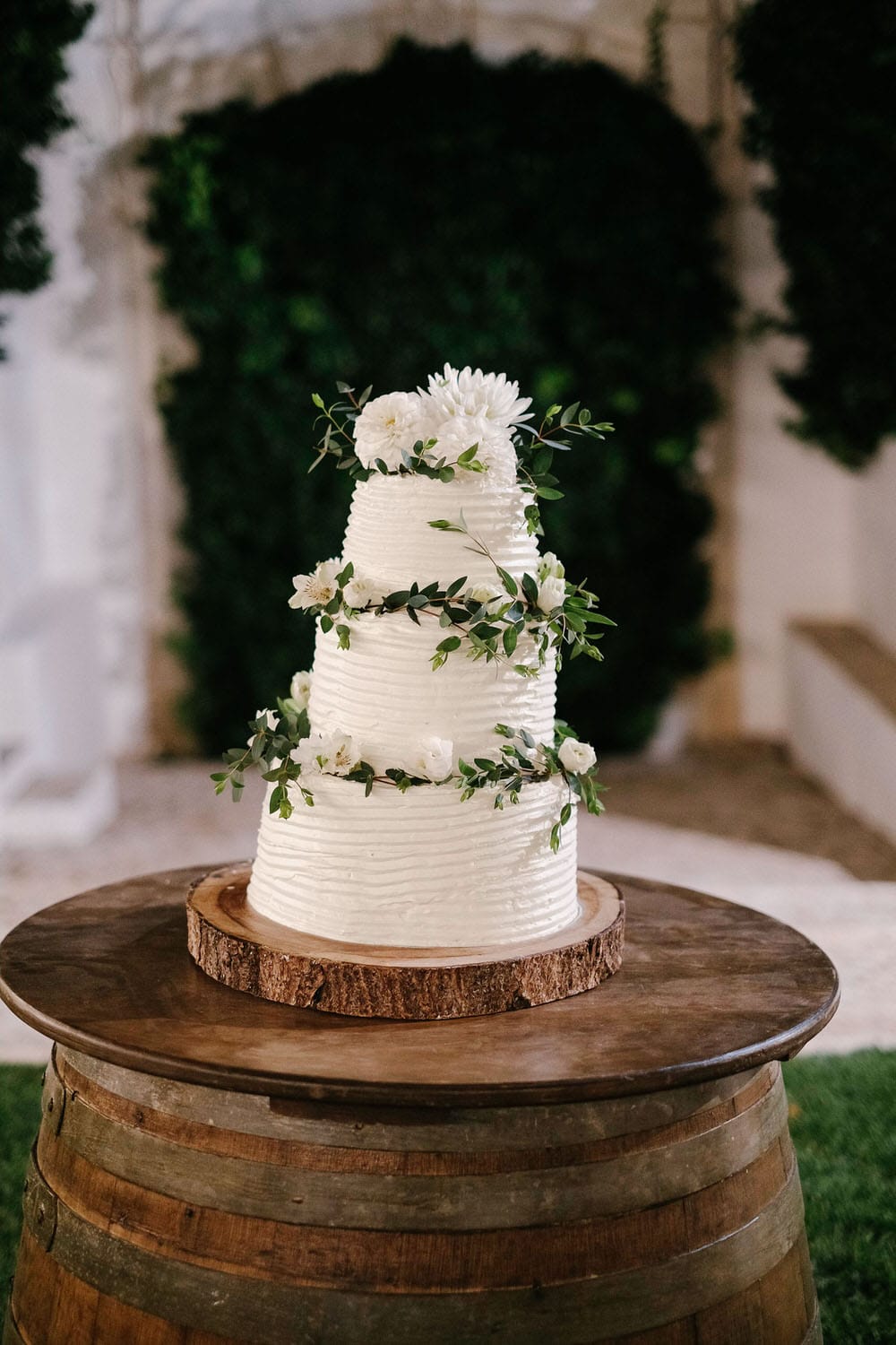 Elegant white wedding cake with stylish green leaves decoration
