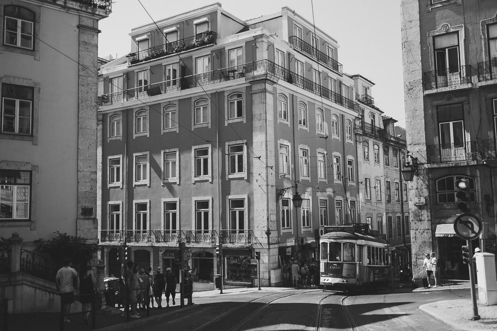 black and white postal of lisbon with a tram going up the old streets