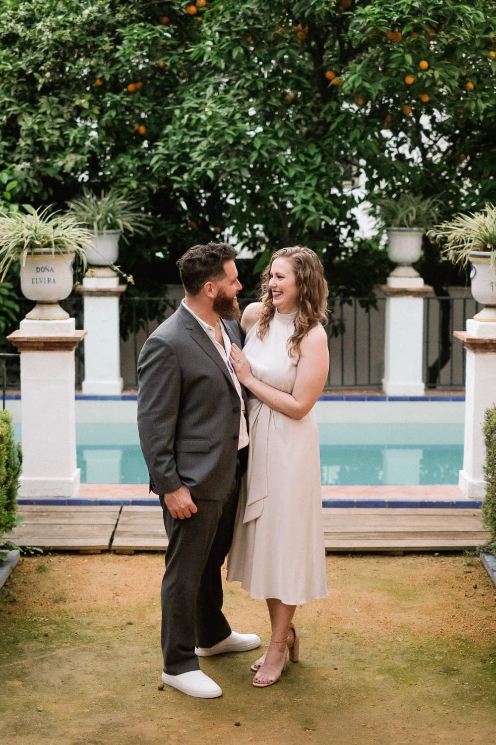 couple smiling each other in front of small pool at private garden in Seville